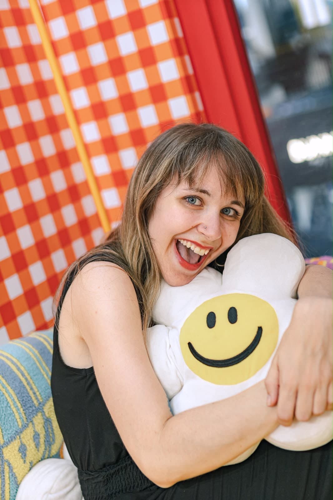 Lena lacht und umarmt ein Smiley-Kissen